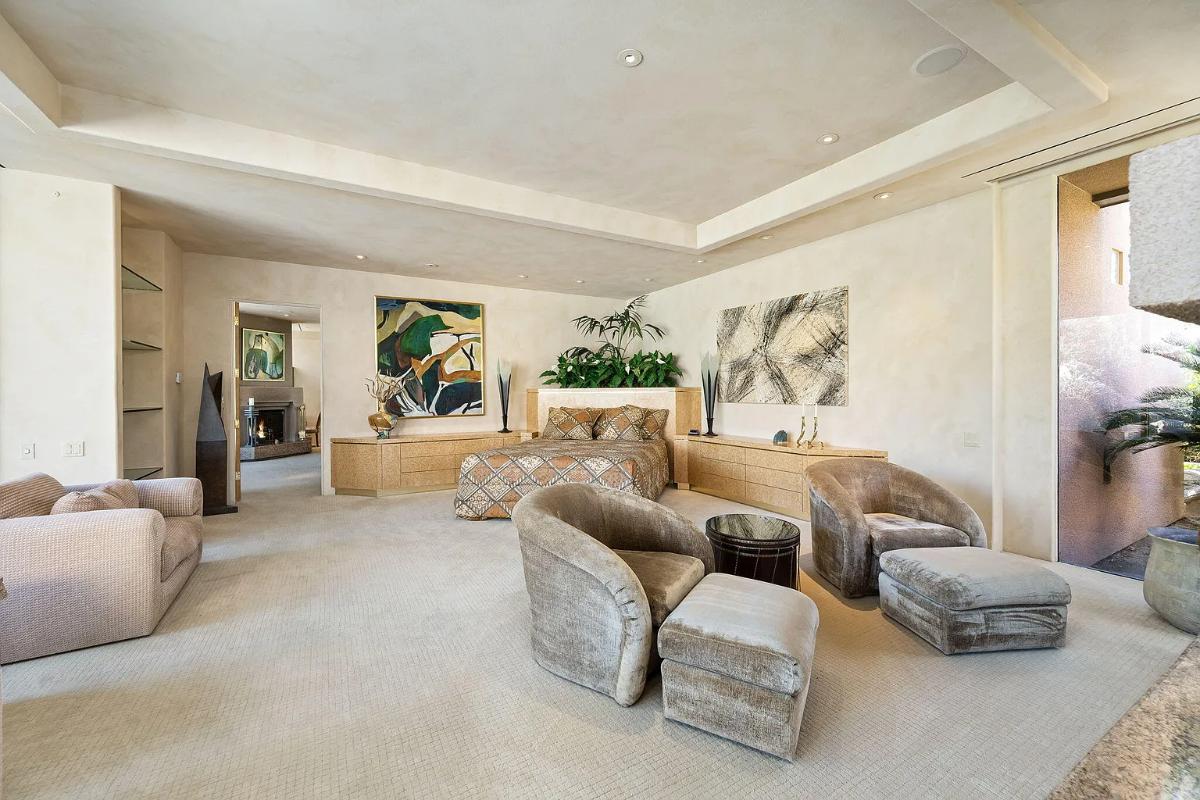 Bedroom with a large bed, couhces and carpet flooring.