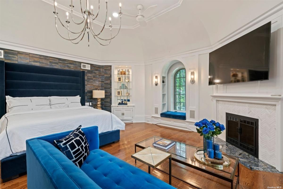 Bedroom with a large bed, a fireplace and hardwood floors.