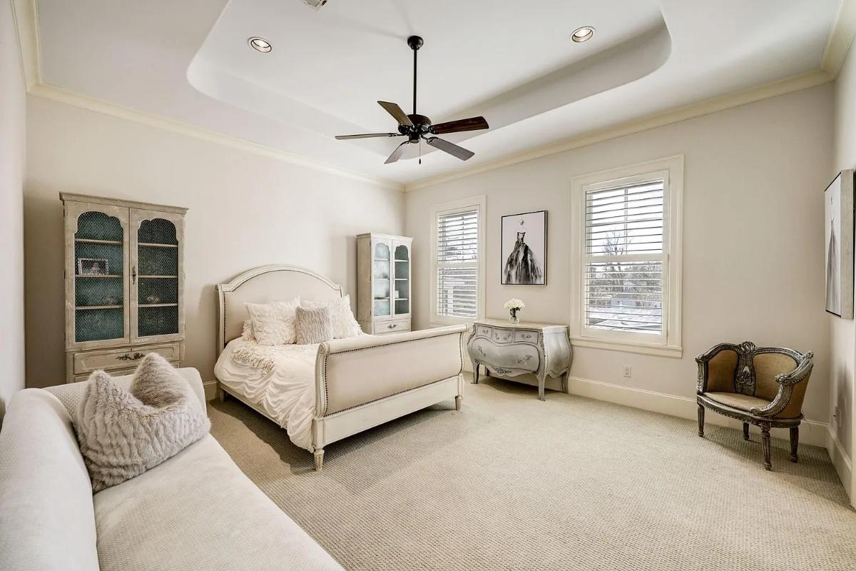 Bedroom with a large bed, a couch and carpet flooring.