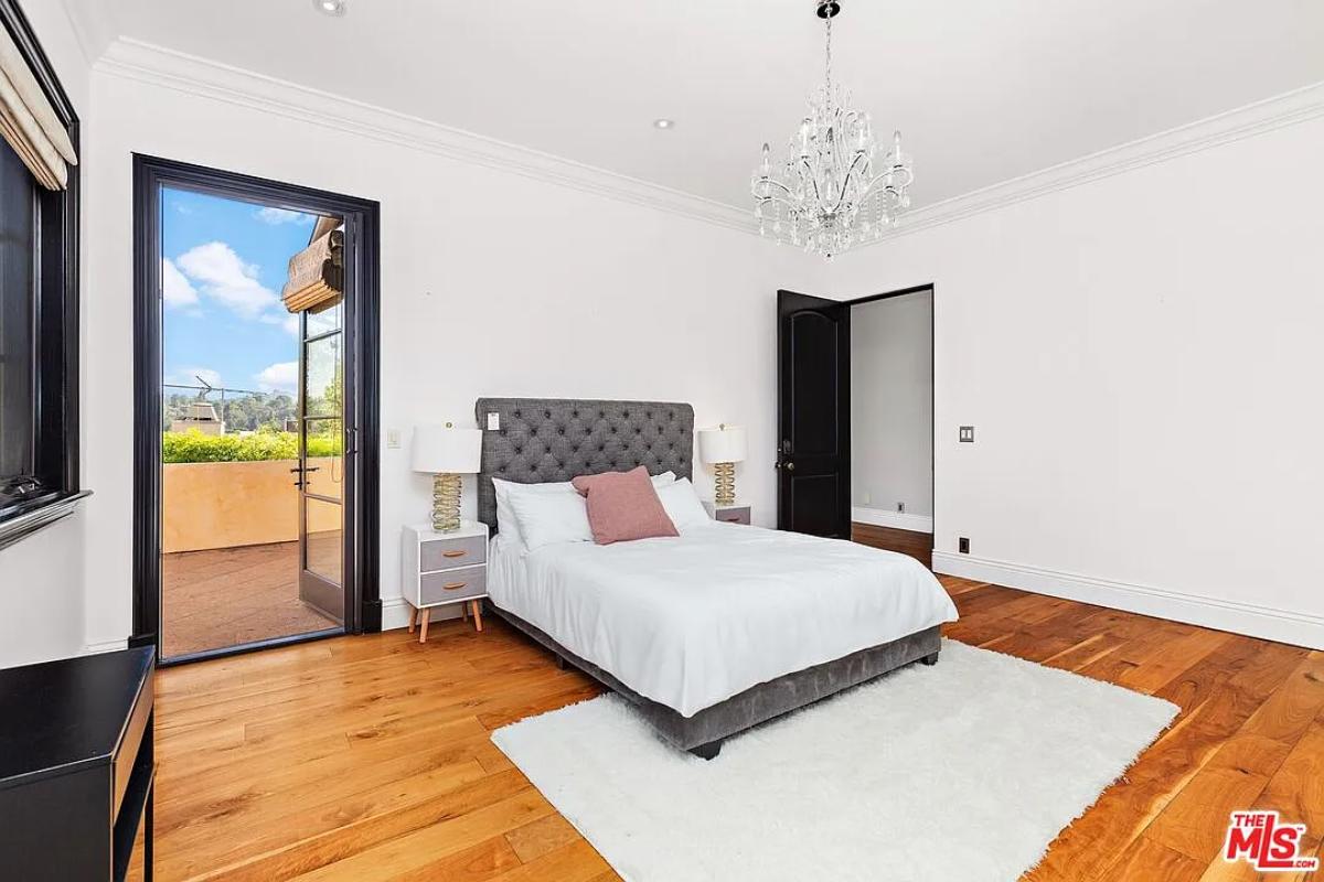 Bedroom with a large bed, a chandelier and hardwood floors.