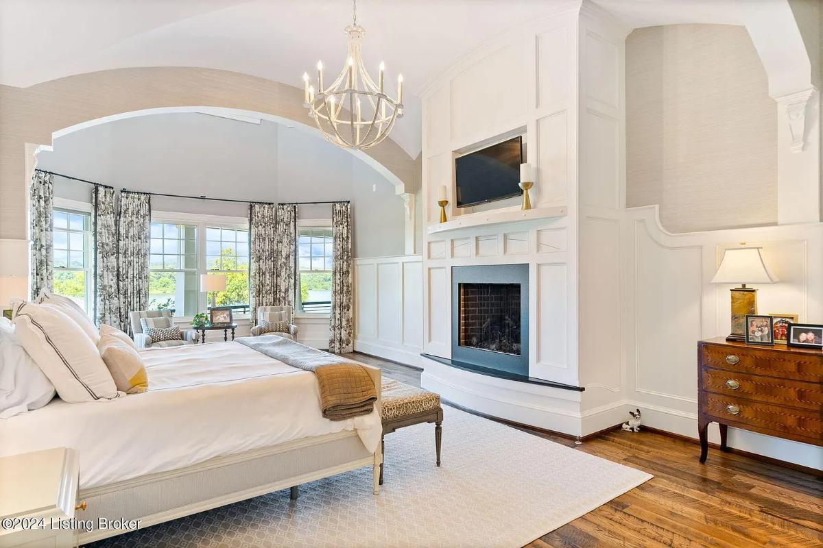 Bedroom with a large bed, a fireplace and hardwood floors.