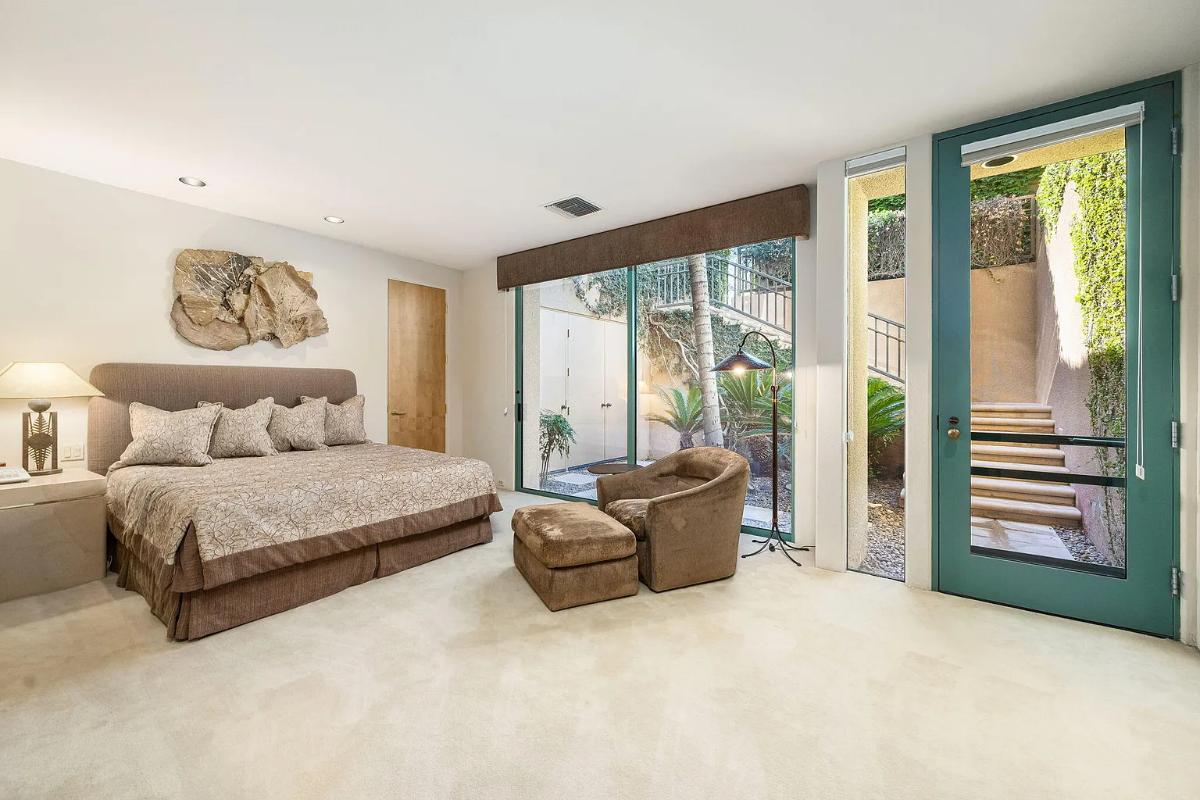 Bedroom with a large bed, glass walls and carpet flooring.