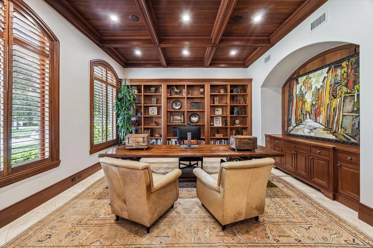 Home office with bookshelves and coffered ceilings.