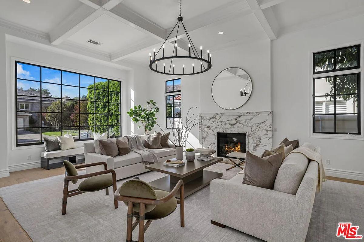 Living room with couches, glass windows and a fireplace.