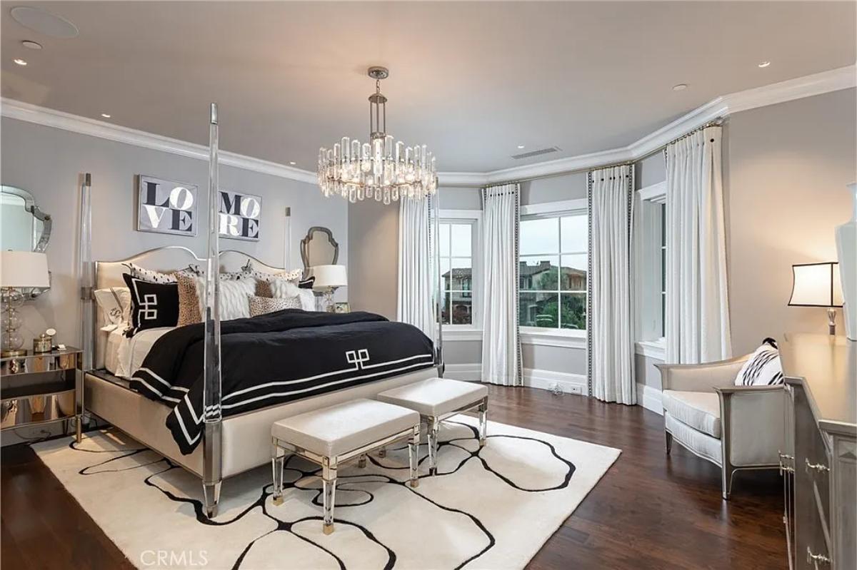 Bedroom with a large bed, chandelier and hardwood floors.