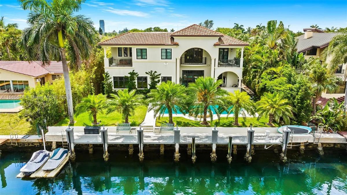 Aerial rear view of the mansion with a pool and a boat dock.