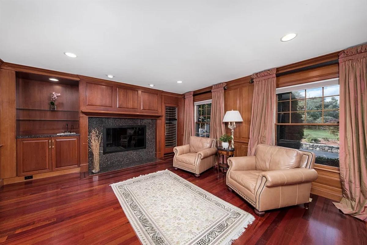 Living room with couches, hardwood floors and a fireplace.
