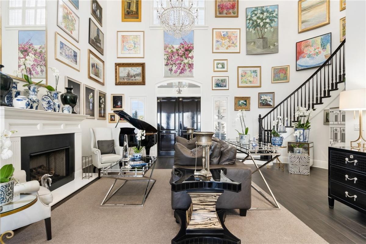 Living room with couches, piano, high ceilings and a fireplace.
