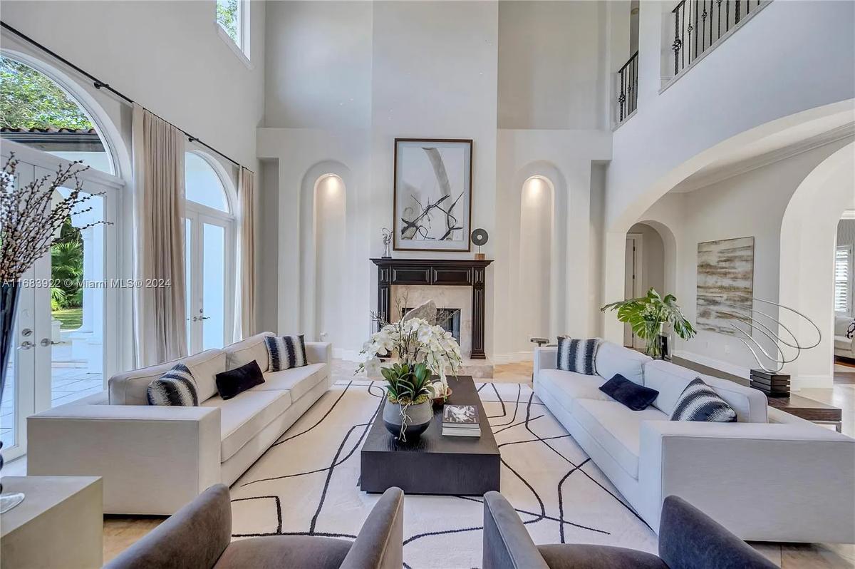 Living room with couches, high ceilings and a fireplace.