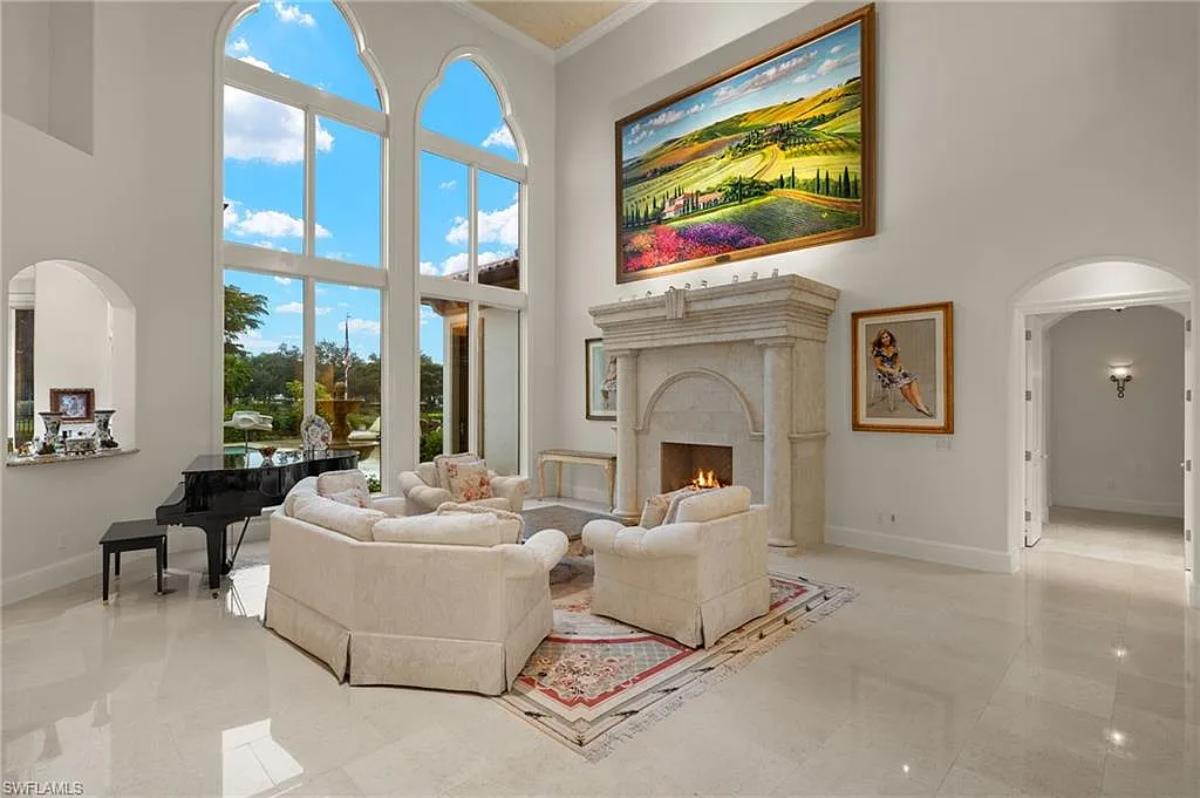 Living room with couches, high ceilings and a fireplace.