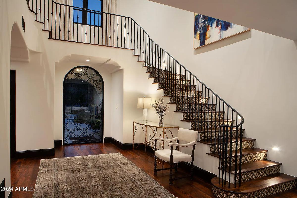 Foyer with hardwood floors and a staircase.