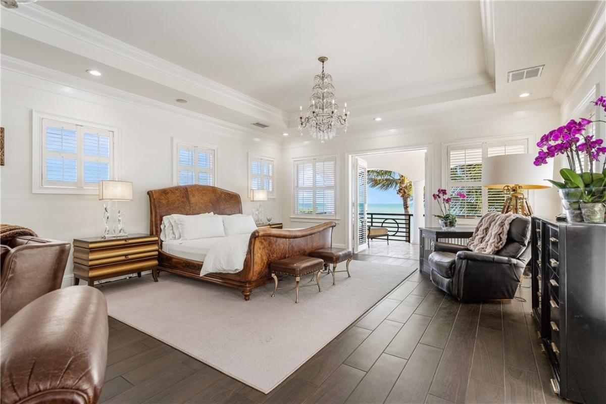 Bedroom with a large bed, chandelier and hardwood floors.