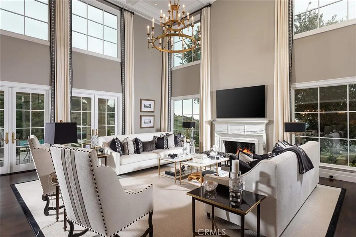 Living room with a chandelier, high ceilings and a fireplace.