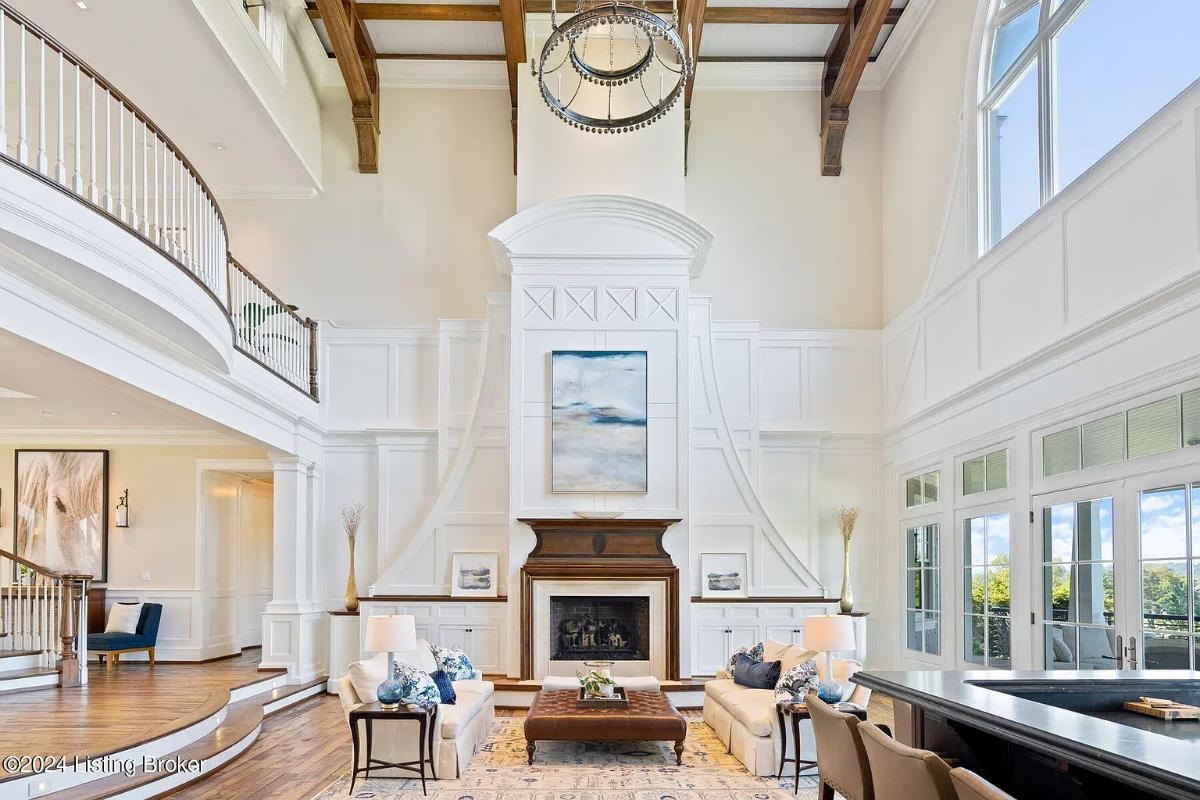 Living room with couches, high ceilings and a fireplace.
