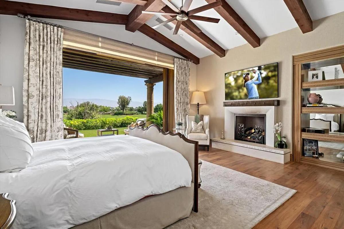 Bedroom with a large bed, a fireplace and hardwood floors.