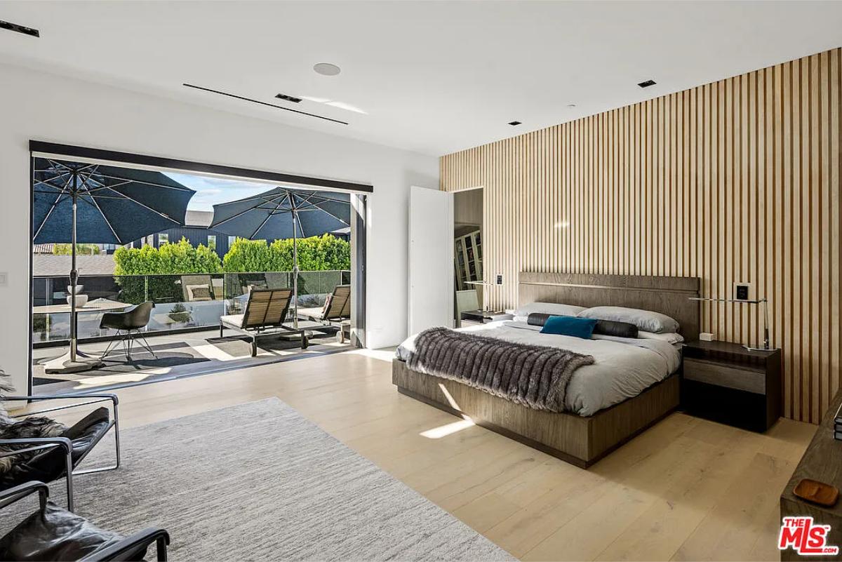 Bedroom with a large bed, sliding glass doors and hardwood floors.
