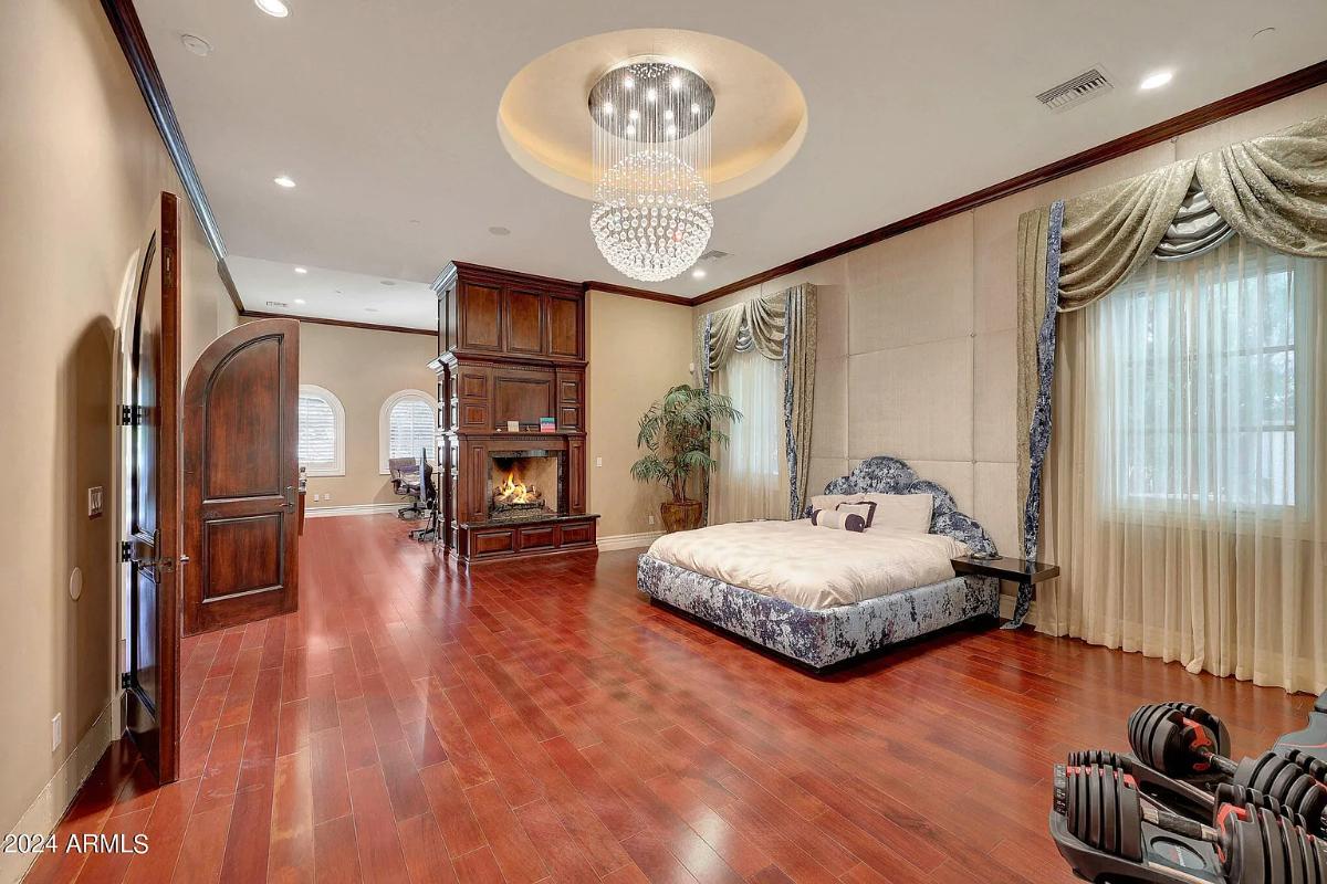 Bedroom with a large bed, a fireplace and hardwood floors.