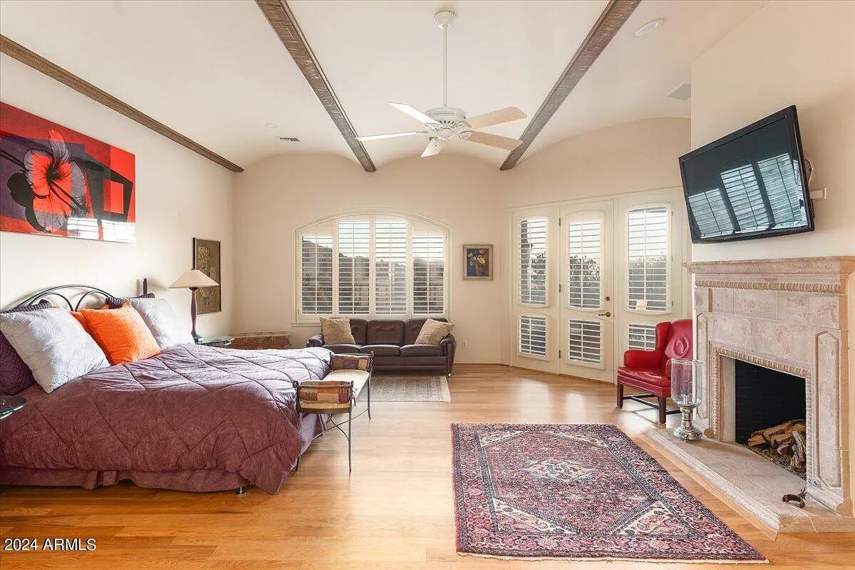 Bedroom with a large bed, a fireplace and hardwood floors.