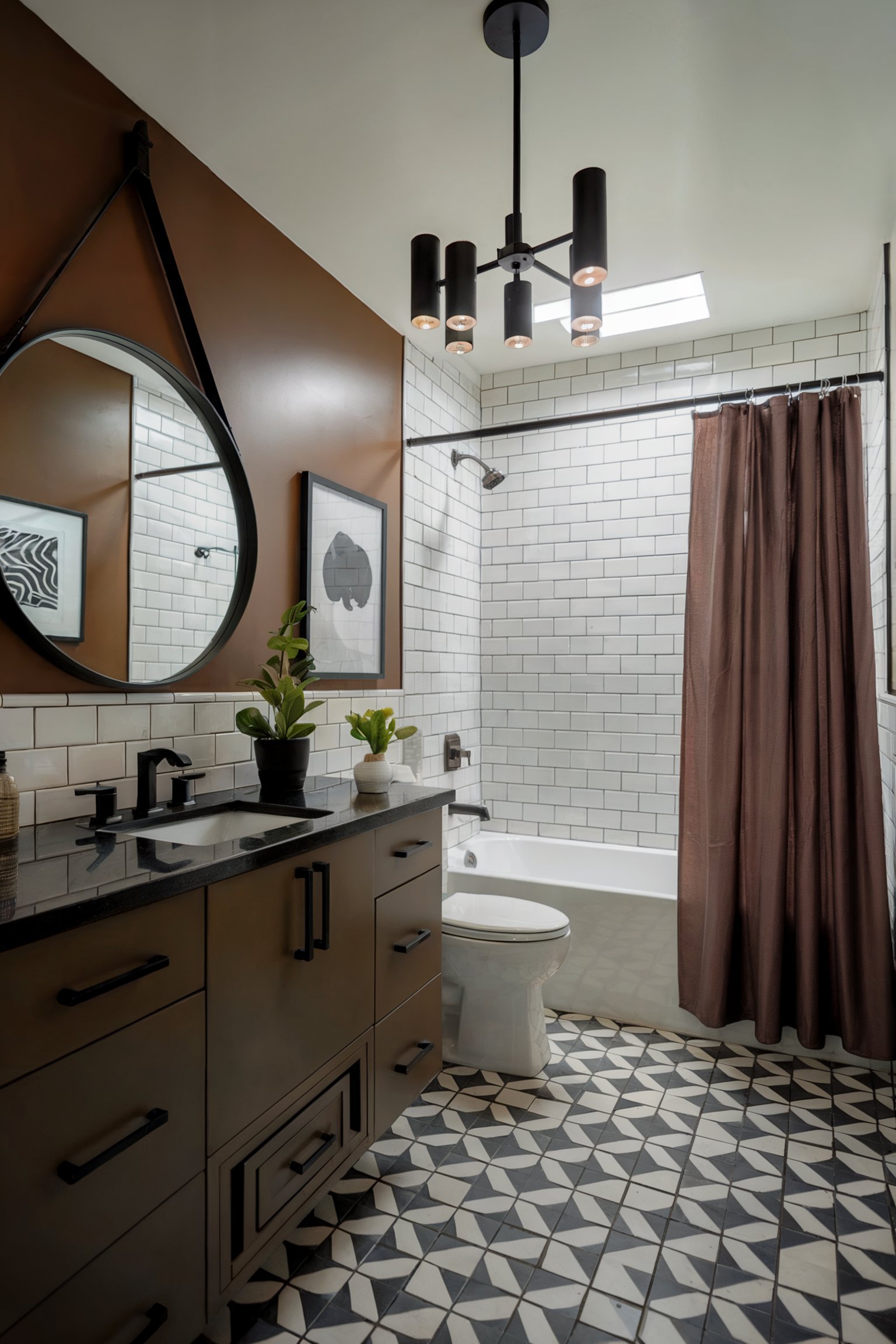 A modern bathroom with a brown accent wall, white subway tile shower, black vanity with a dark countertop, geometric floor tiles, and a round mirror