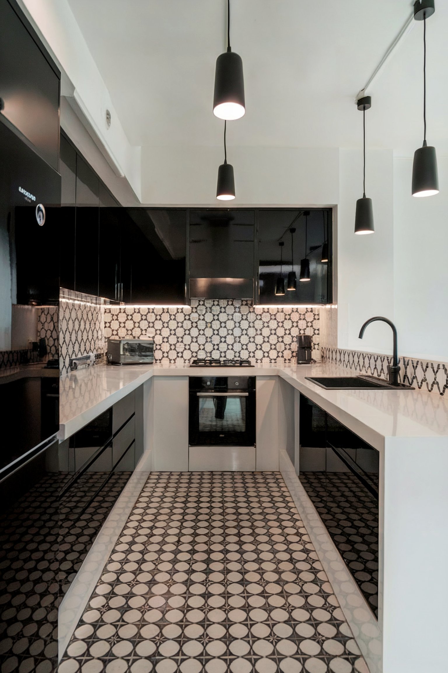 A sleek, modern kitchen with glossy black cabinets, geometric patterned tiles, and minimalist hanging pendant lights