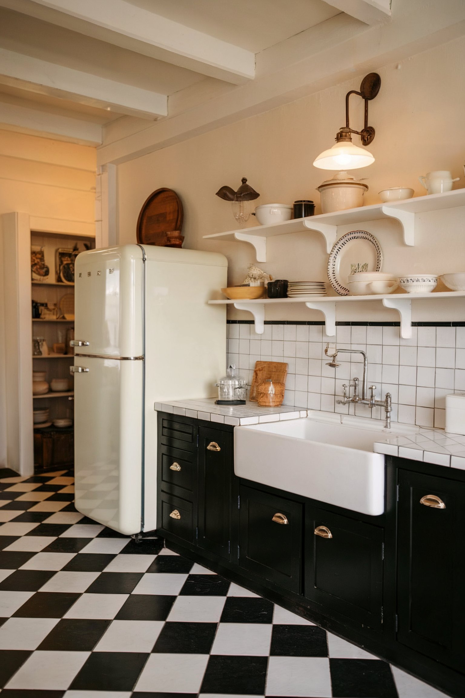 A vintage-inspired kitchen with open shelves, black cabinets, a farmhouse sink, and checkered tile flooring