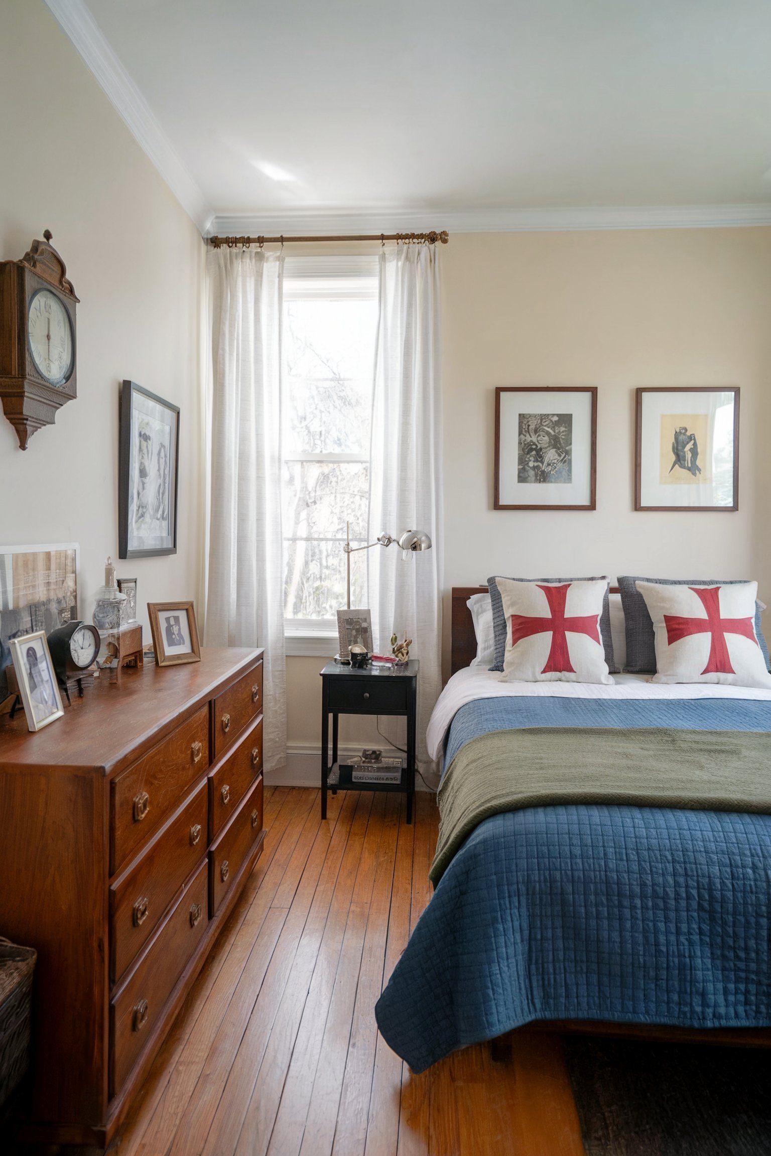 A vintage-themed bedroom with a wooden dresser, framed art, and a bed with decorative pillows against a classic decor