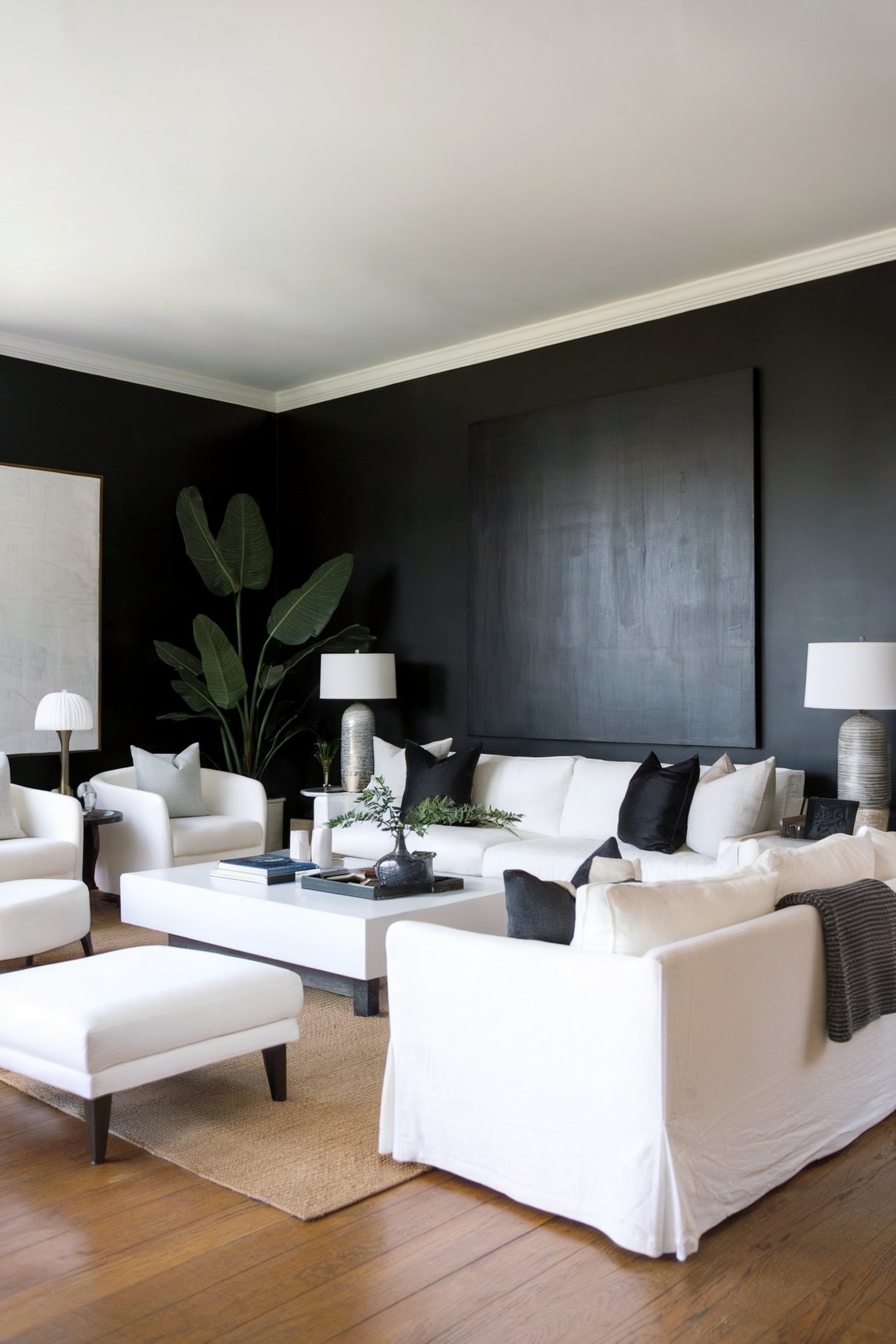 A bright living room with white furniture, black pillows, and a large black accent wall, creating a bold contrast