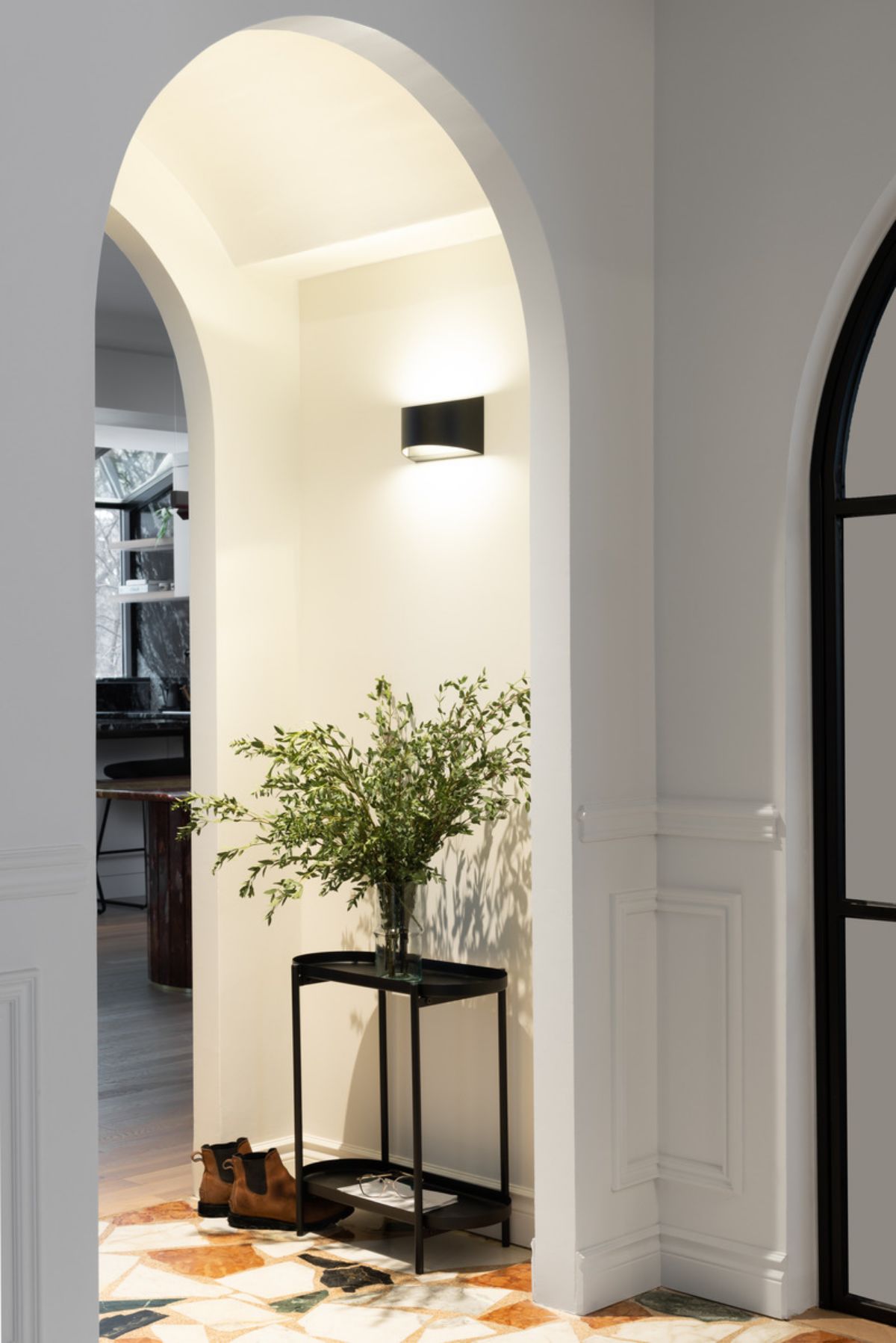 Main entrance of the house with graceful arches and side table with a plant ornament on top