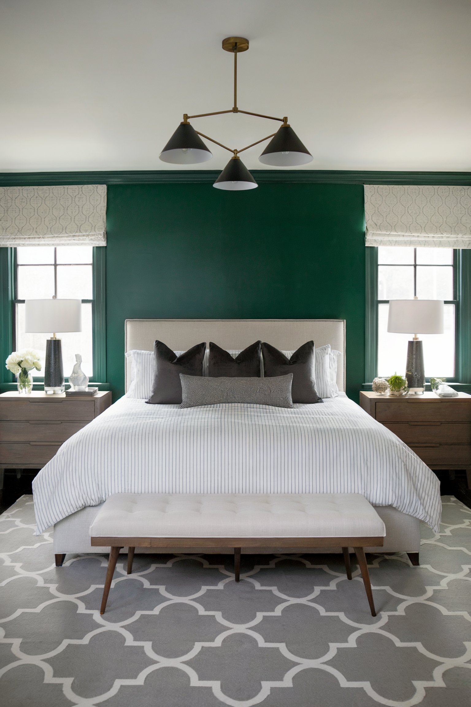 Elegant bedroom with a bold emerald green accent wall, flanked by windows, and a bed adorned with black and gray pillows