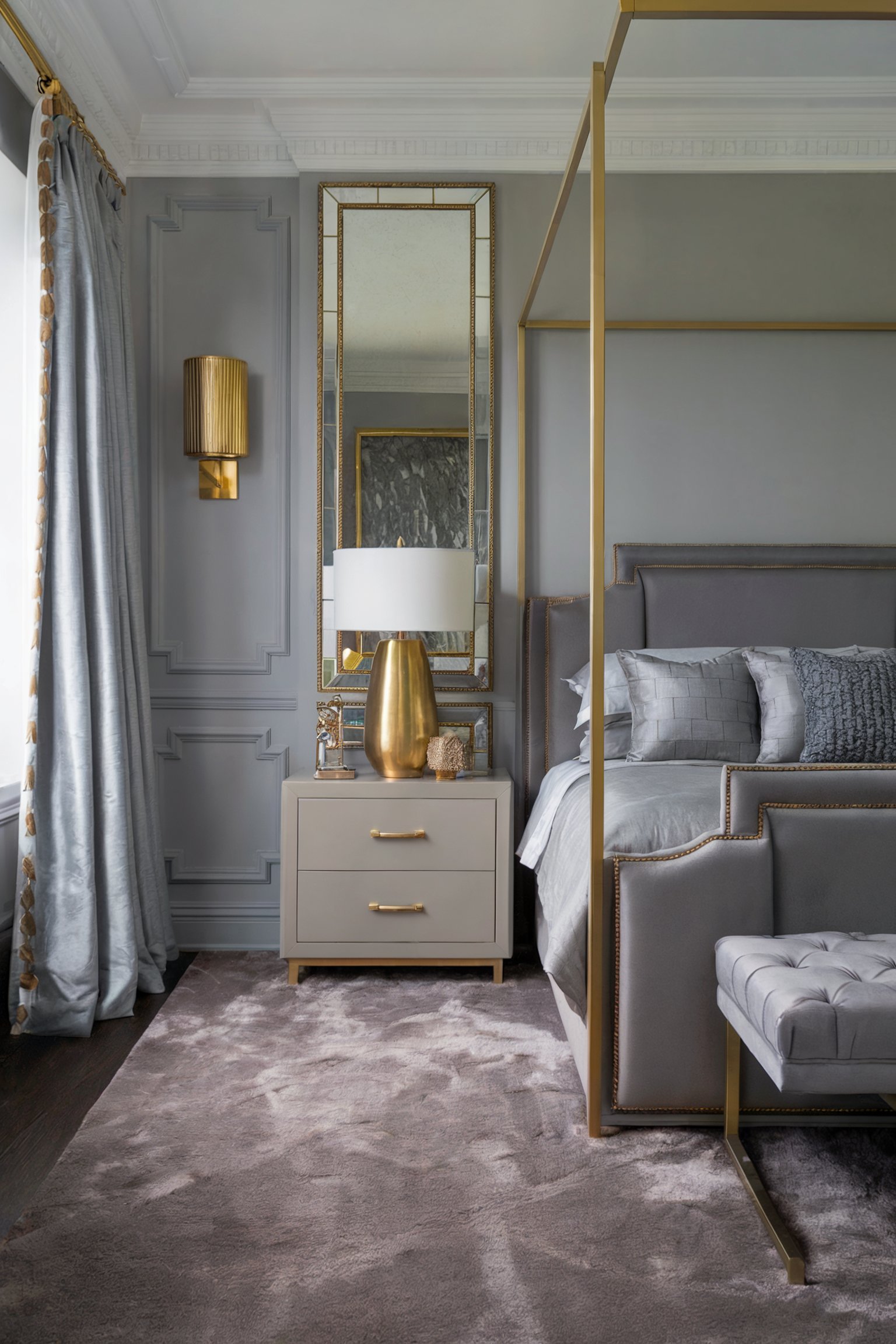 Elegant grey bedroom with a four-poster bed, gold accents, and mirrored nightstand