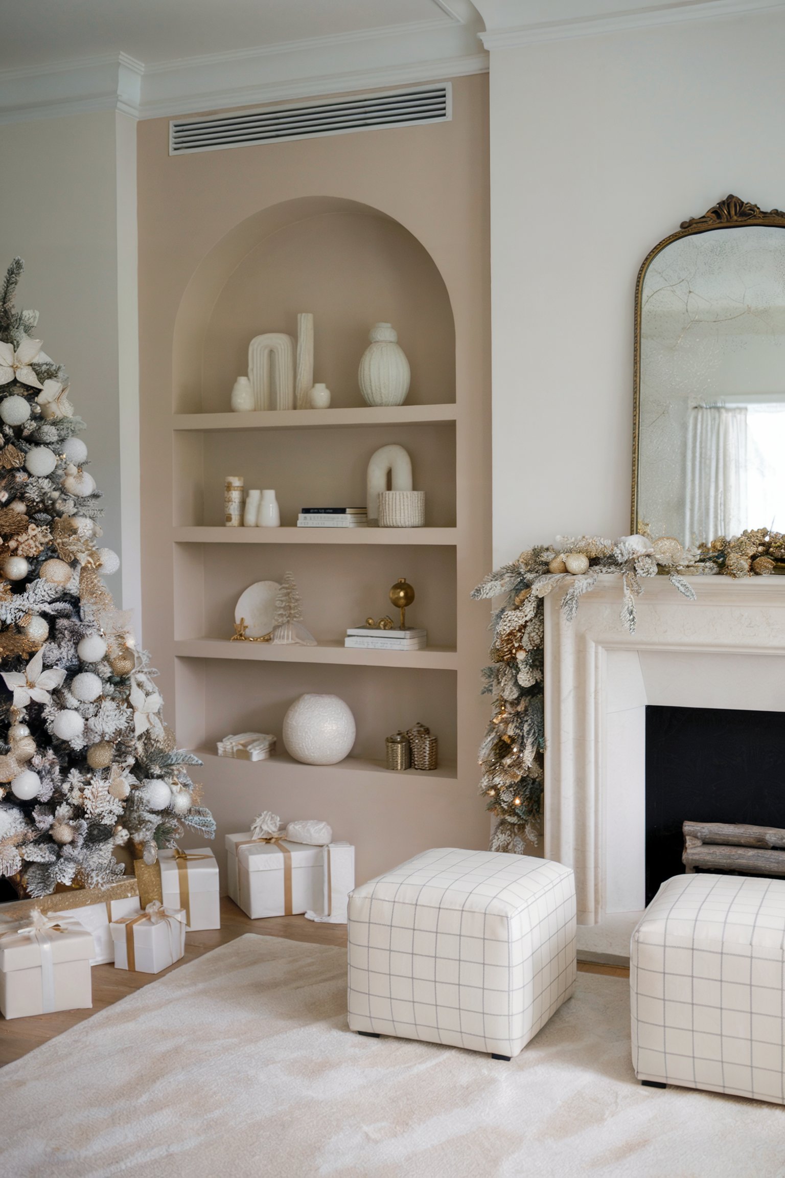 Modern Christmas living room with a flocked tree decorated in neutral tones, matching garland on the mantel, minimalistic shelves, and a large mirror