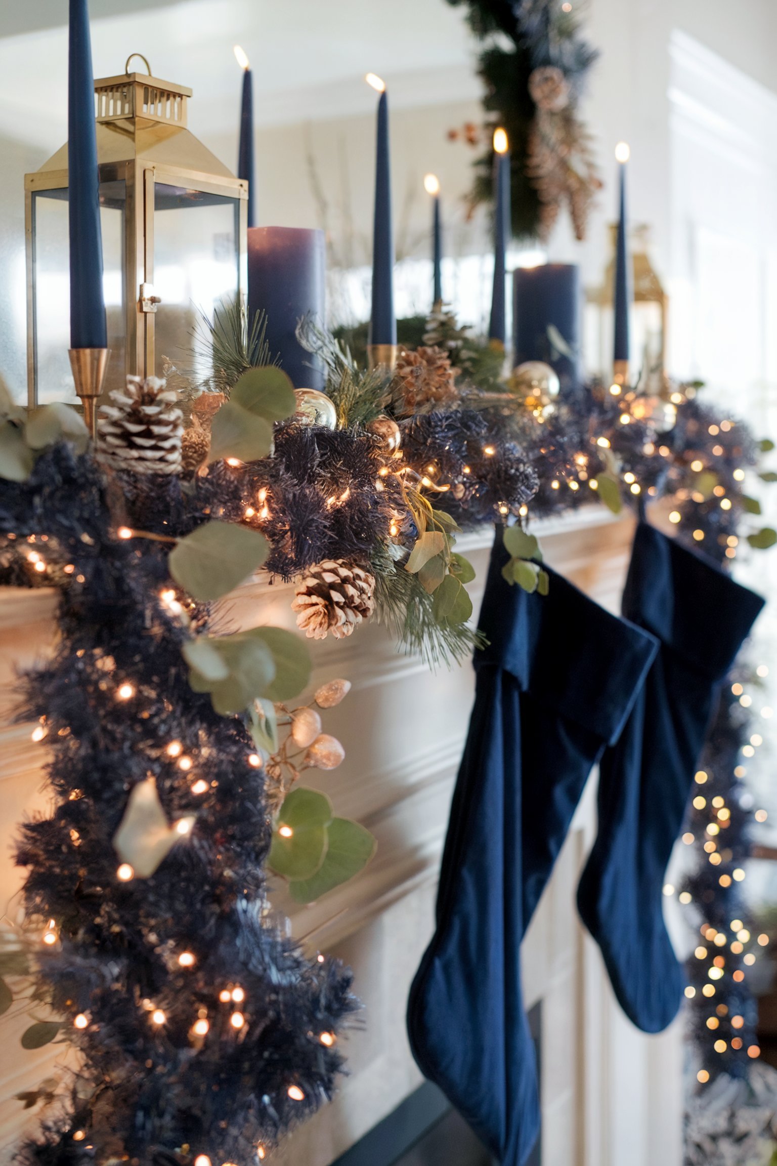 A chic Christmas mantel adorned with navy blue candles, pine cones, and festive greenery