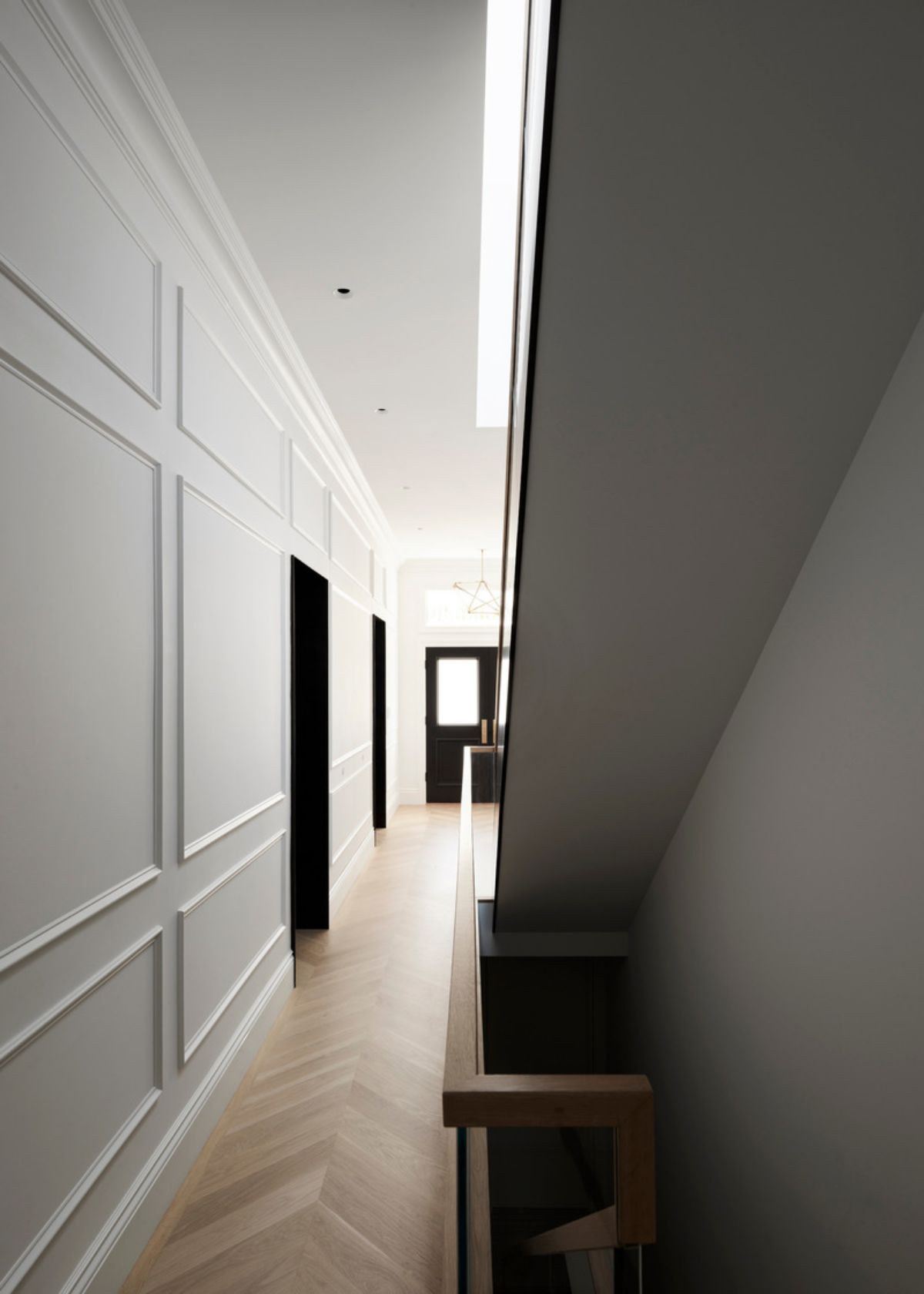 Modern meets timeless when alcoves framed with blackened steel punctuate the wood paneling and wainscoting.