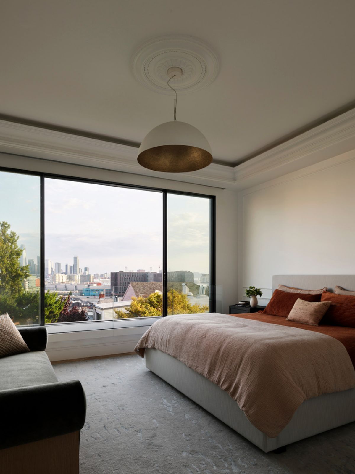 From the primary bedroom, the view includes a variety of architectural styles, from traditional to contemporary and modern. The chaise longue was sourced by Niche Interiors.