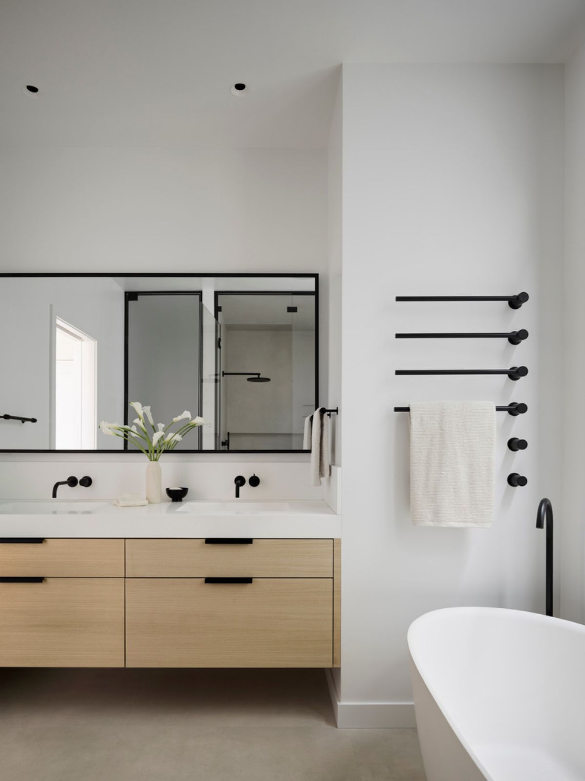 In the primary bathroom, the double bowl sink, which is integrated into the counter, and the soaking tub, both in matte white, are from MTI.
