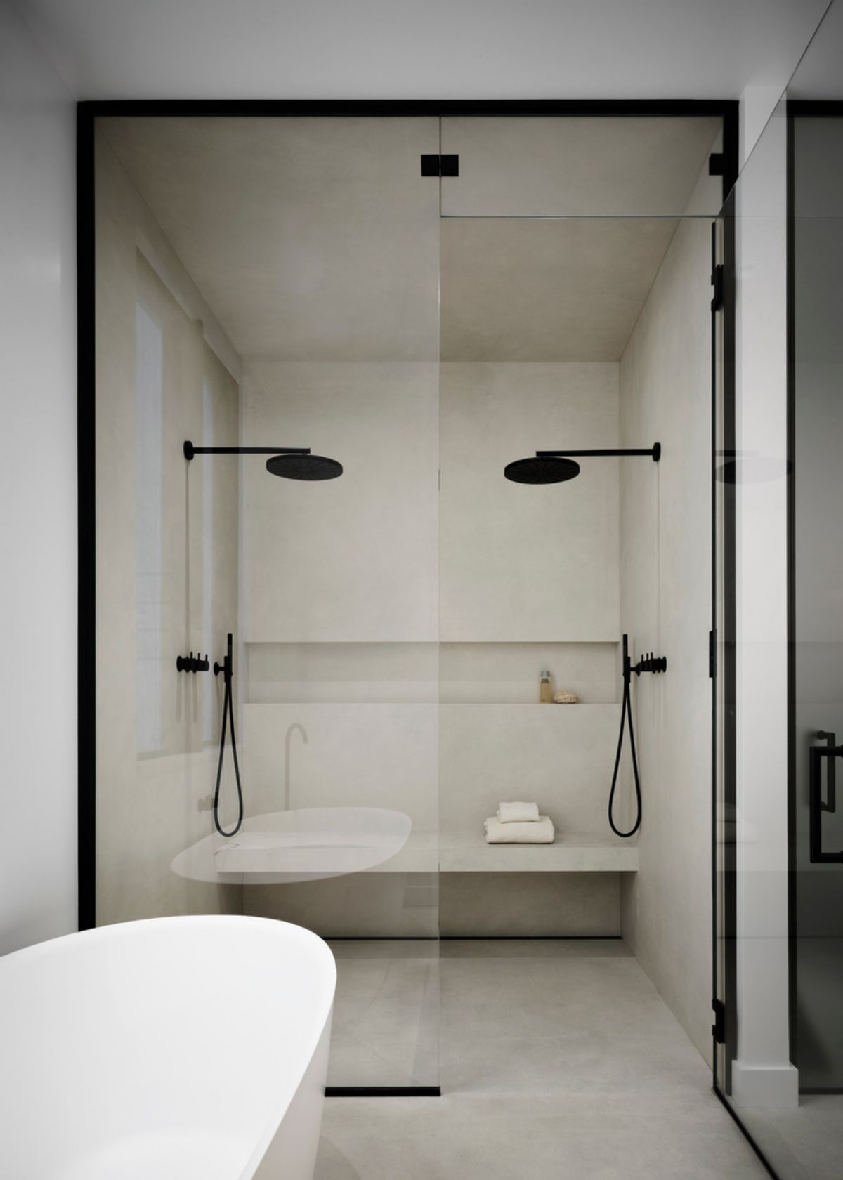 Calce Bianco Natural Porcelain sets off the round wall mounted shower heads in matte black from Vola.