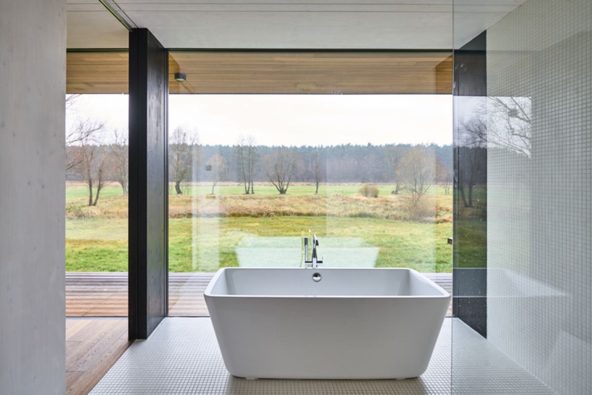 The main feature is a large freestanding bathtub positioned in front of a floor-to-ceiling window