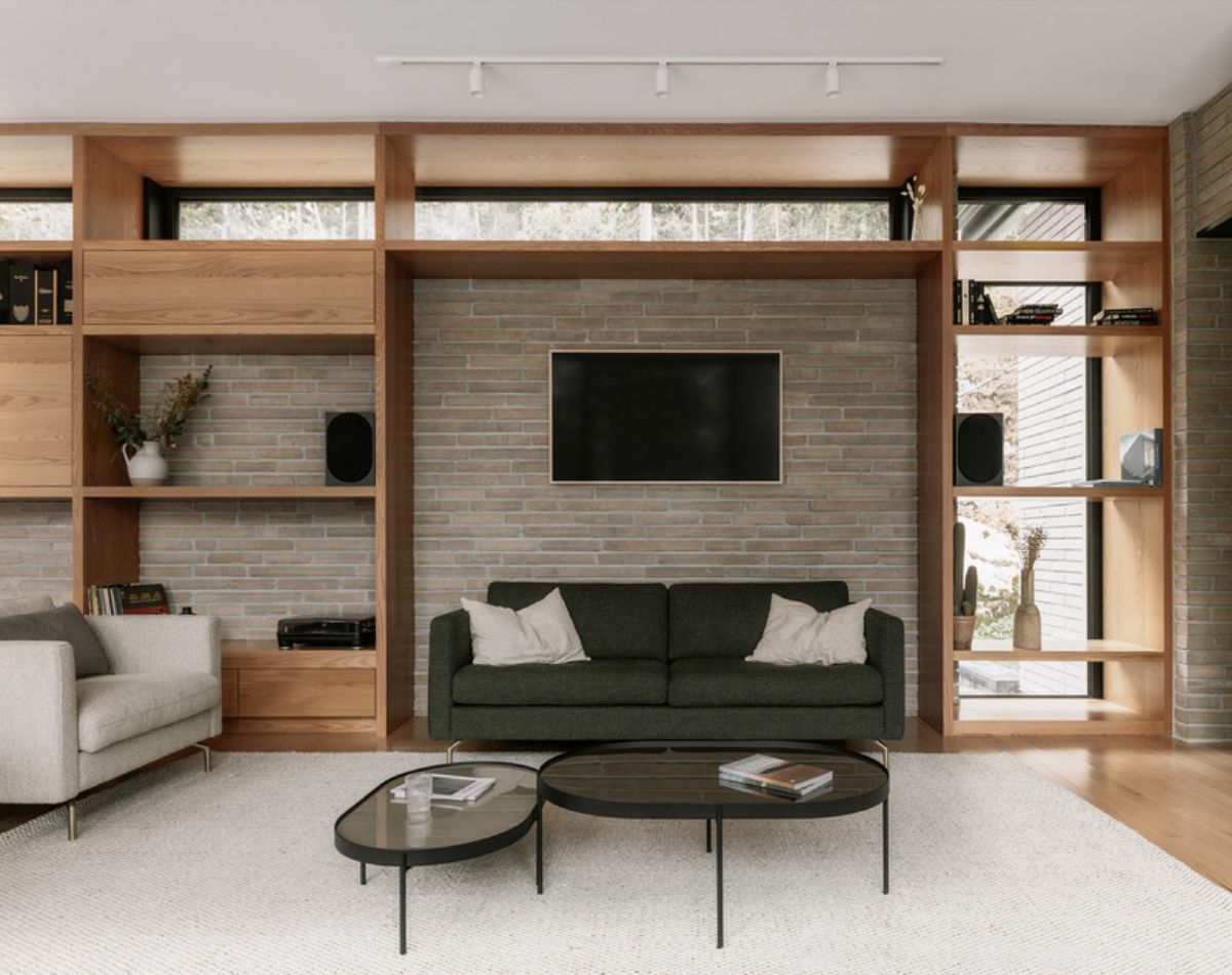 A continuous red oak bookshelf extends throughout the length of the house. The upper row of the bookshelf includes windows overlooking the backyard, allowing natural light to filter through the space.