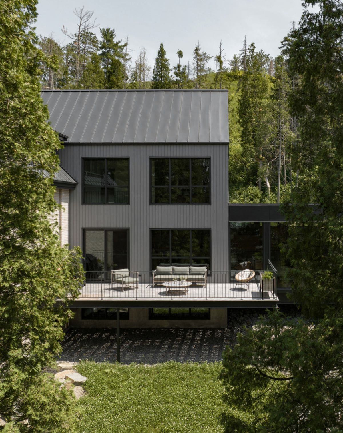 Side view of the house with large glass windows and with balcony