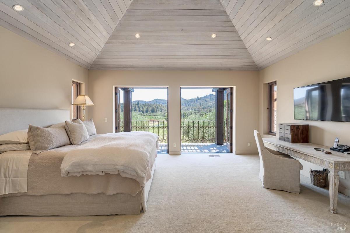 Bedroom with a desk, bed, and double doors opening to an outdoor view.