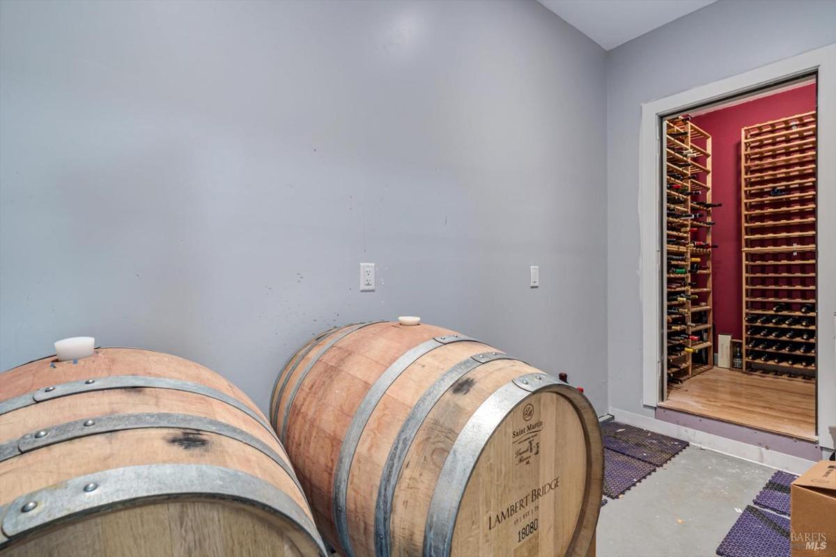 Room with wine barrels and a wine storage area in the background.