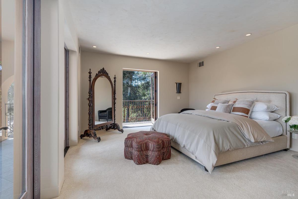 Bedroom with a large mirror, cushioned bed, and a balcony door.