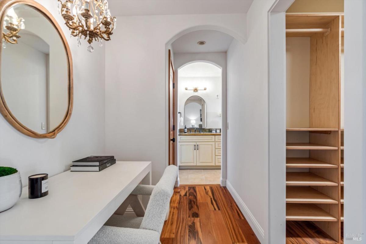 Small desk area with a mirror, chandelier, and access to a bathroom.