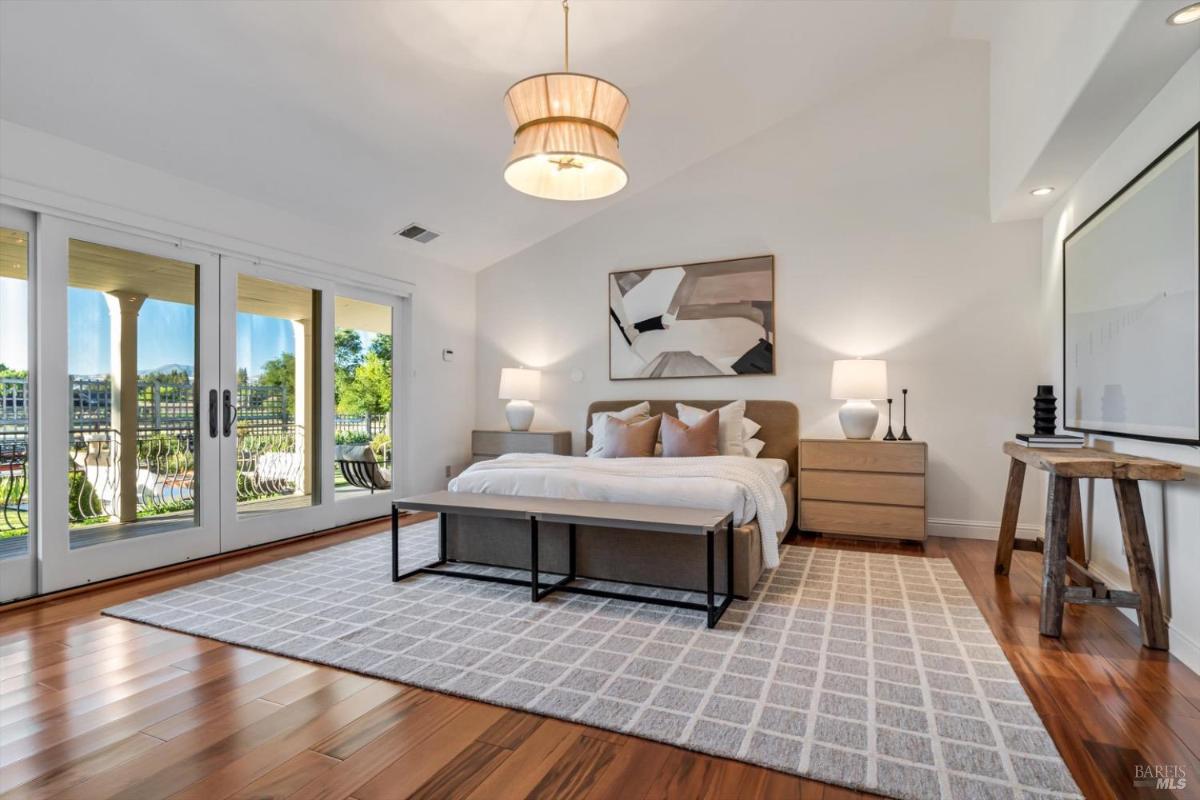 Bedroom with a bed, nightstands, and large windows opening to a patio.
