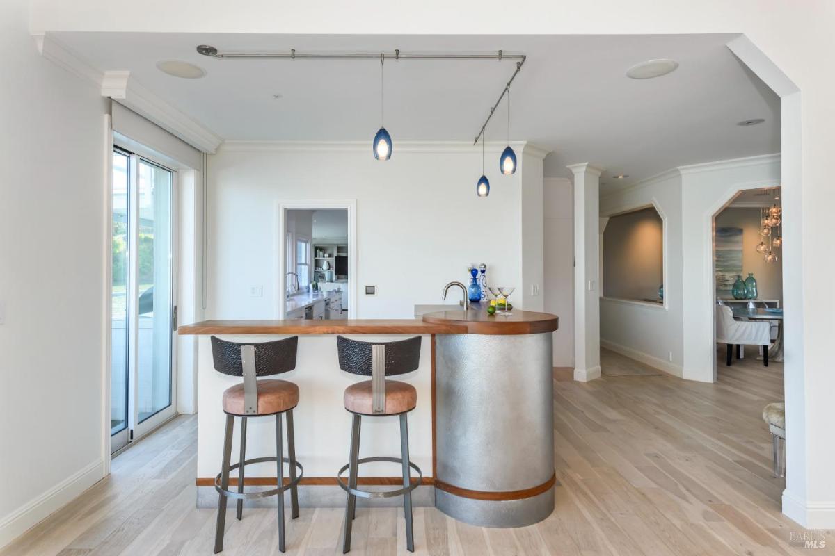 A small bar area with two stools, pendant lights, and access to adjacent rooms.