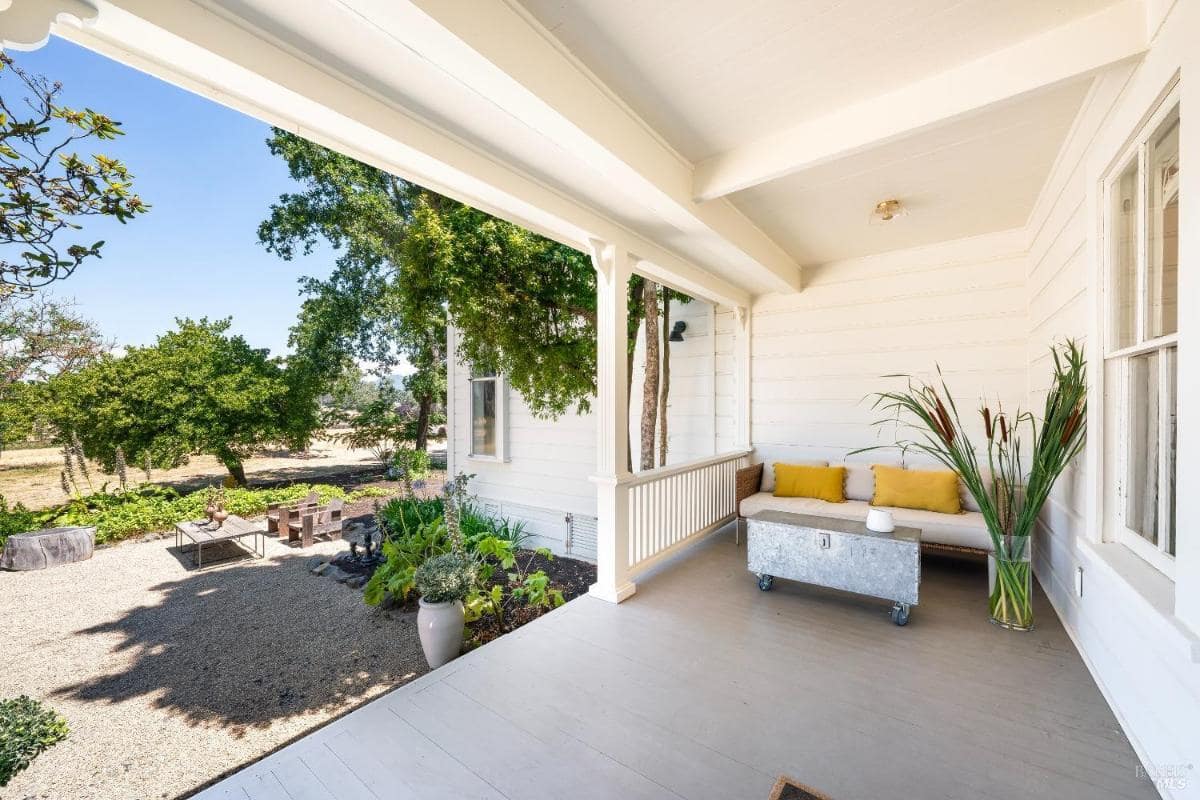 Covered porch with seating and views of a landscaped yard.