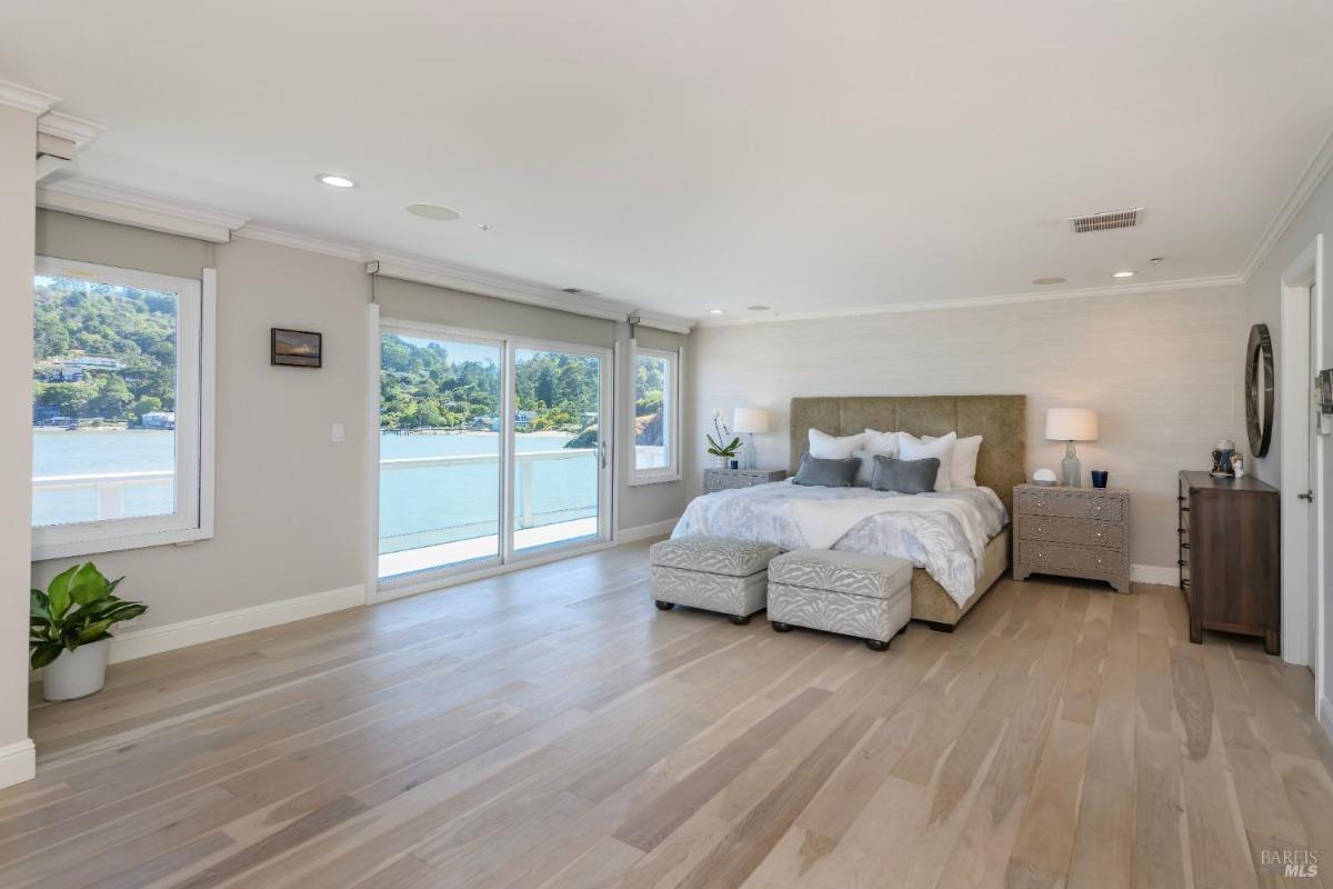 A bedroom with large windows, a king-size bed, and a view of the water.