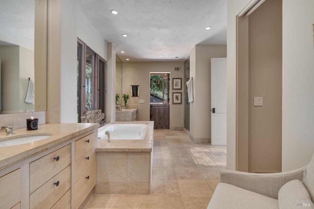 Bathroom with a built-in tub, double sinks, and an exterior door.