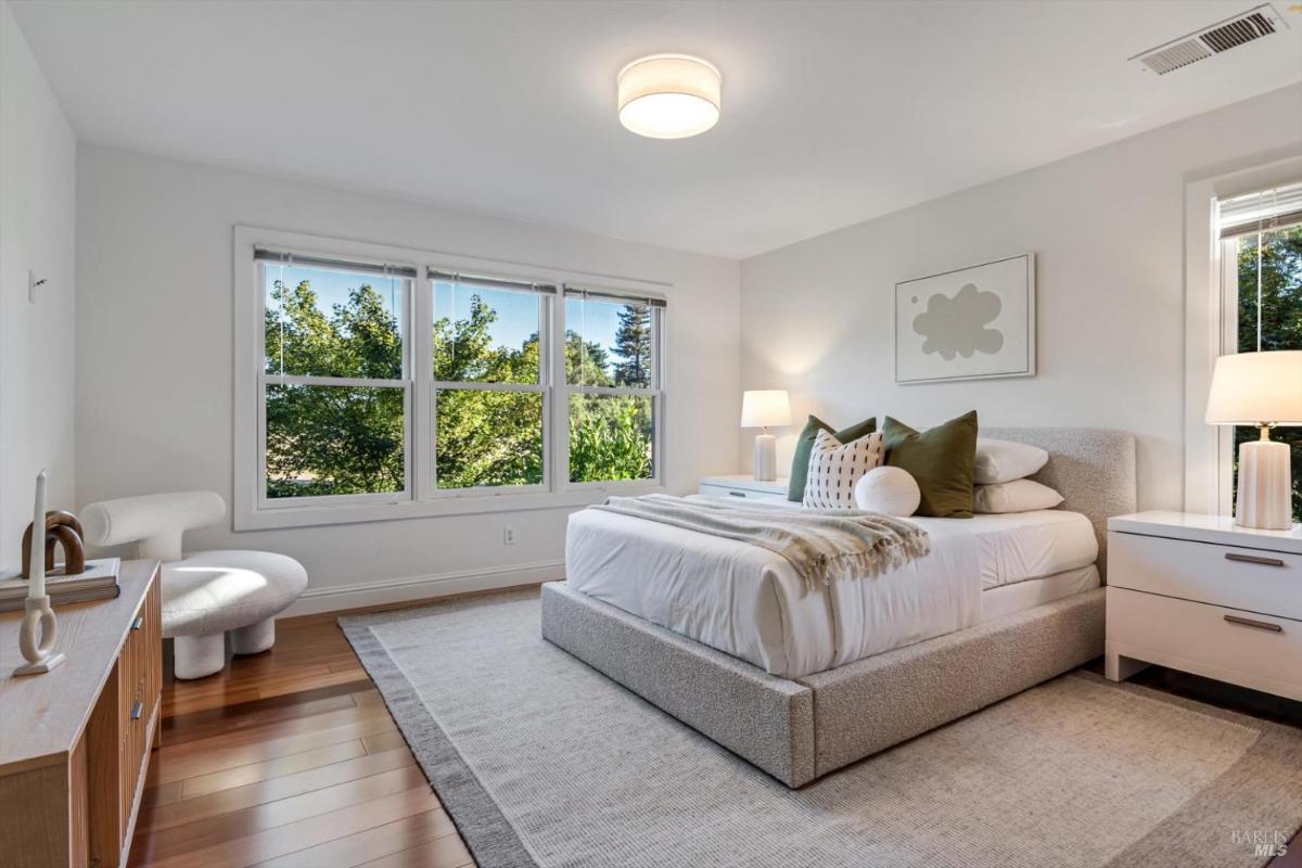 Bedroom with large windows, a bed, and a small seating area.