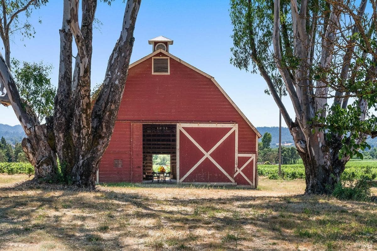 Exterior view of a red barn surrounded by trees.